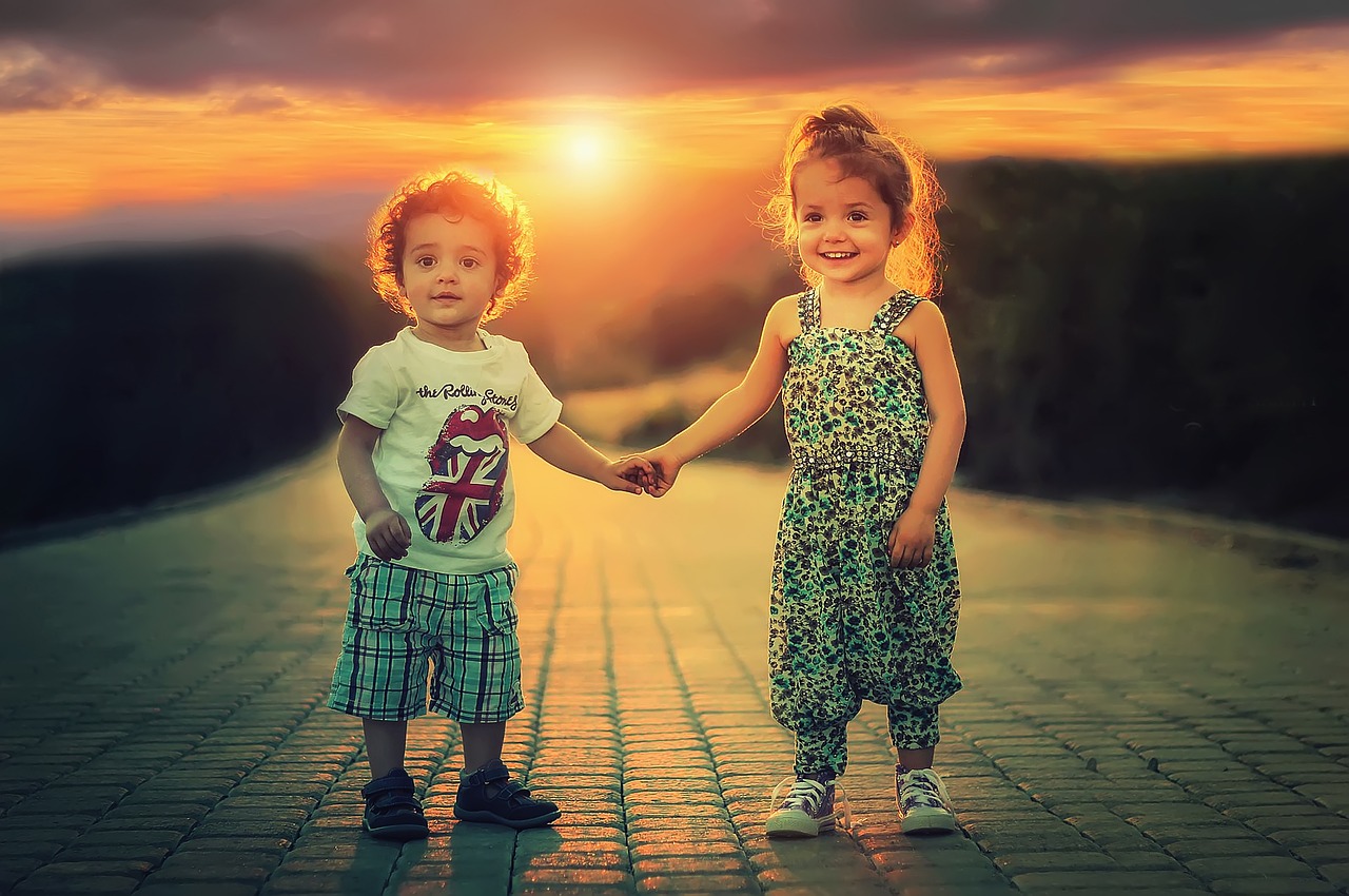 dzieci trzymają się za ręce na tle zachodu słońca